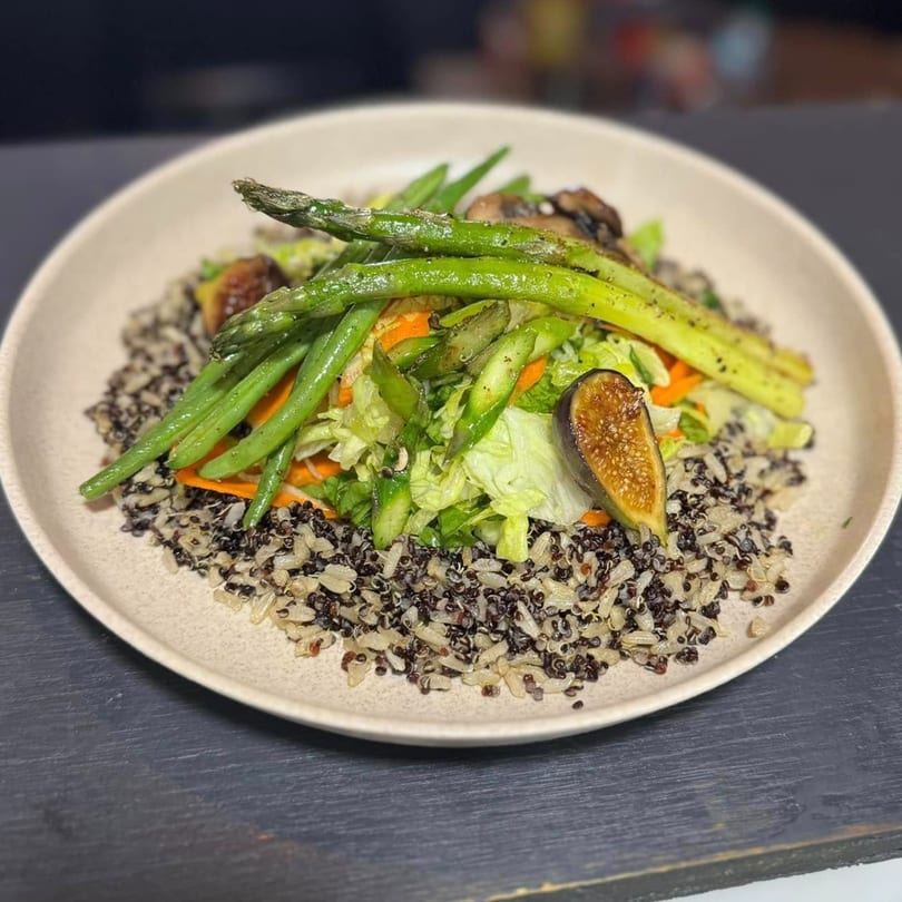 A vibrant La Gruta Signature Cuisine salad with asparagus, figs, and mixed greens over quinoa.