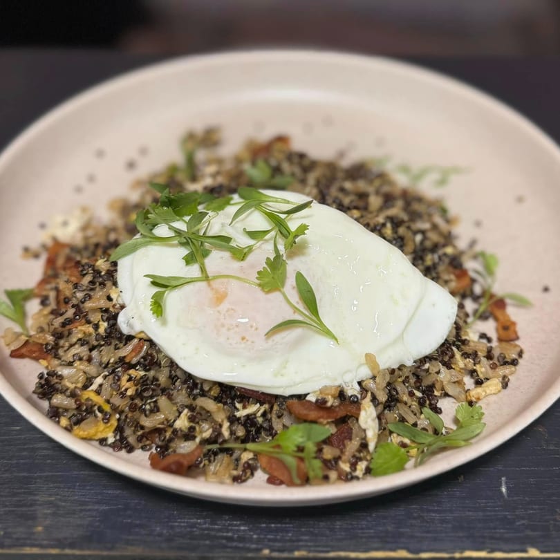 A La Gruta Signature Cuisine dish with black lentils, onions, and a fried egg topped with herbs.